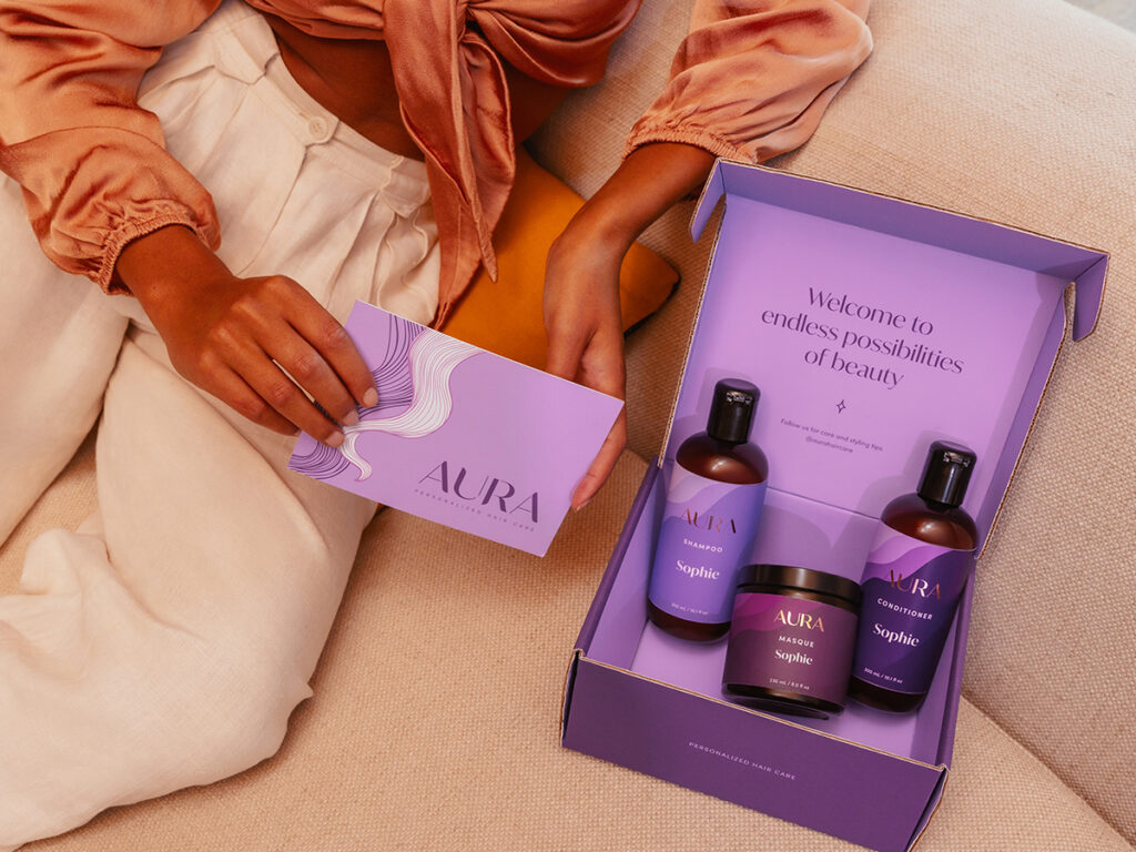 Girl opening AURA box with a hair Masque, Shampoo, and Conditioner inside. 