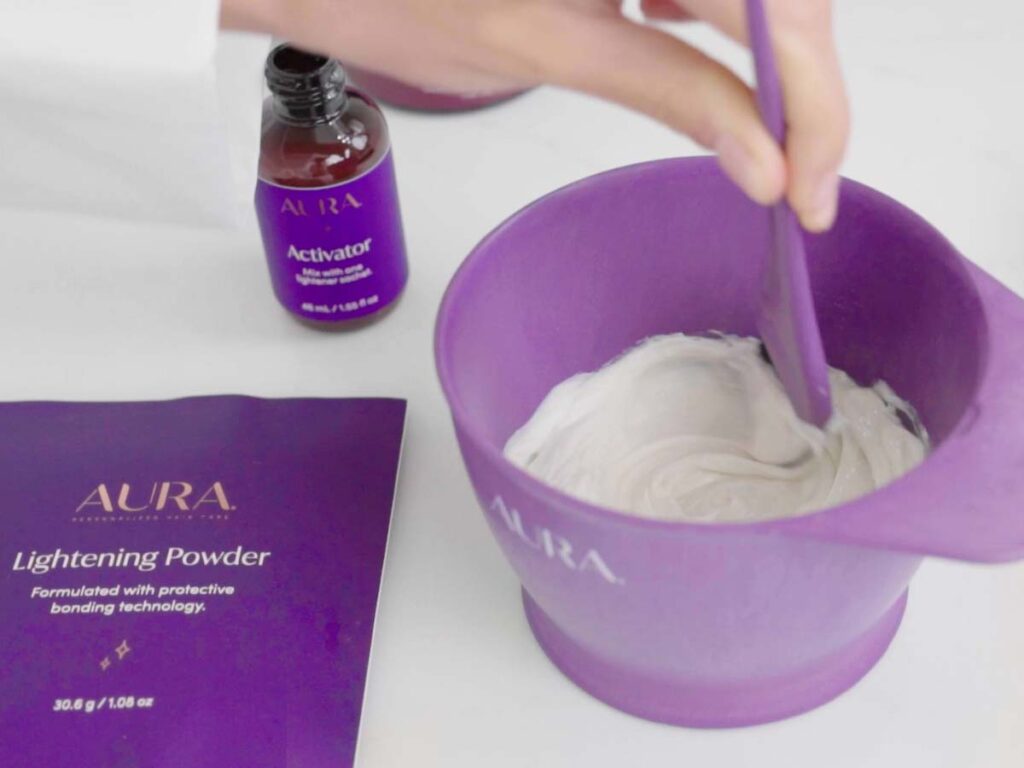 Model stirs the Lightening Powder and the Activator together in a non-metal mixing bowl with Coloring Brush until the formula has an icing-like consistency. 