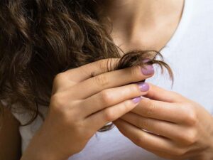 Person touching the dry ends of their hair