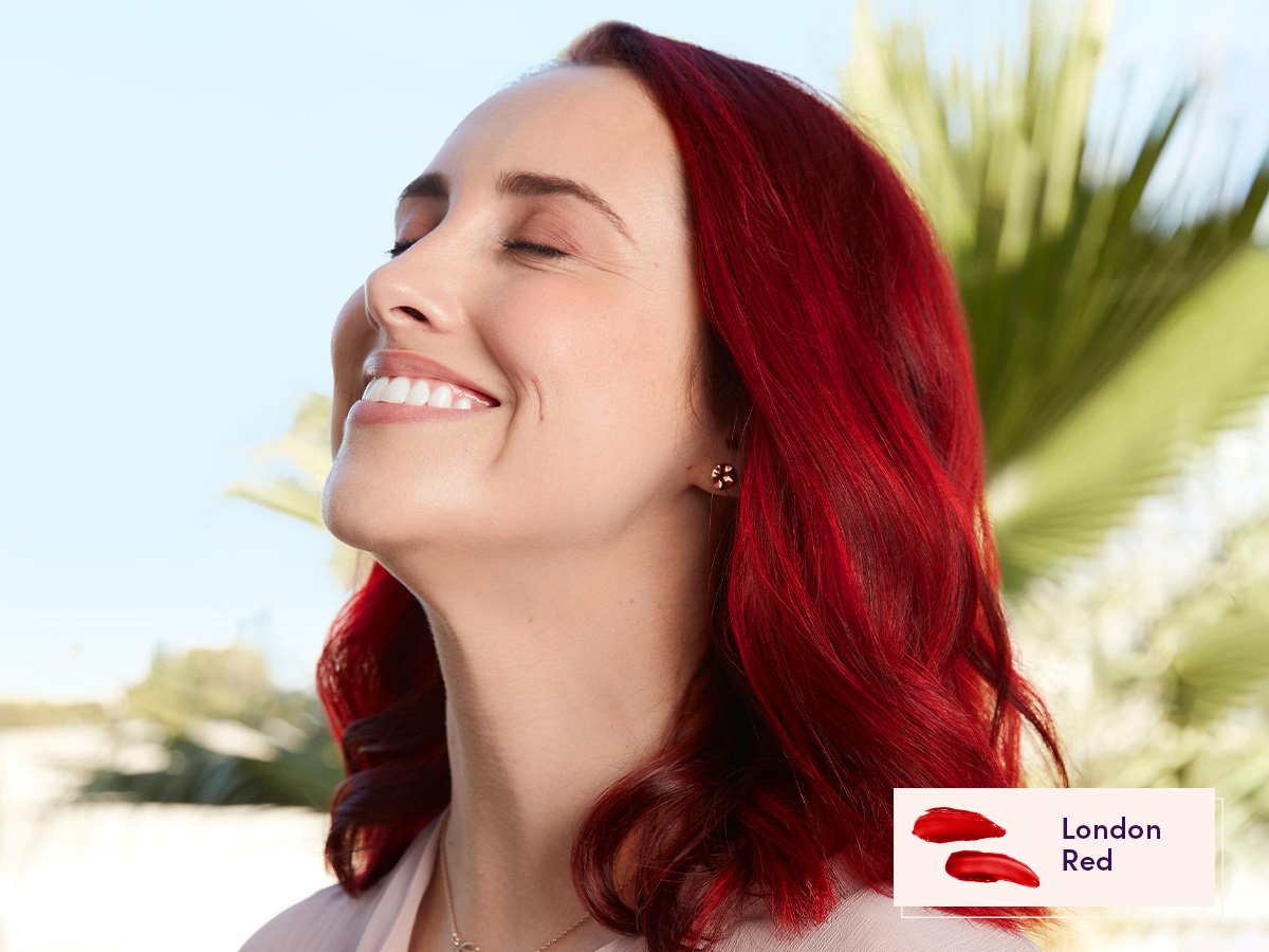 Smiling AURA Color Muse with warm skin tone. She has our semi-permanent pigment in Fantasy shade London Red in her hair.