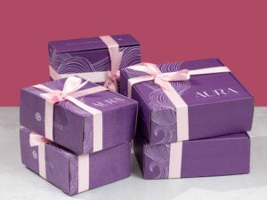 Five purple AURA boxes wrapped in light pink ribbons as presents.
