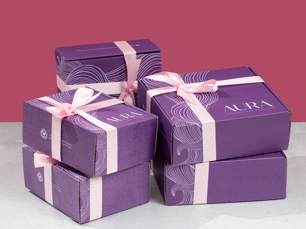 Five purple AURA boxes wrapped in light pink ribbons as presents.