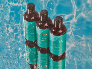 Three bottles of our skin-nourishing body wash against a water-drenched background.