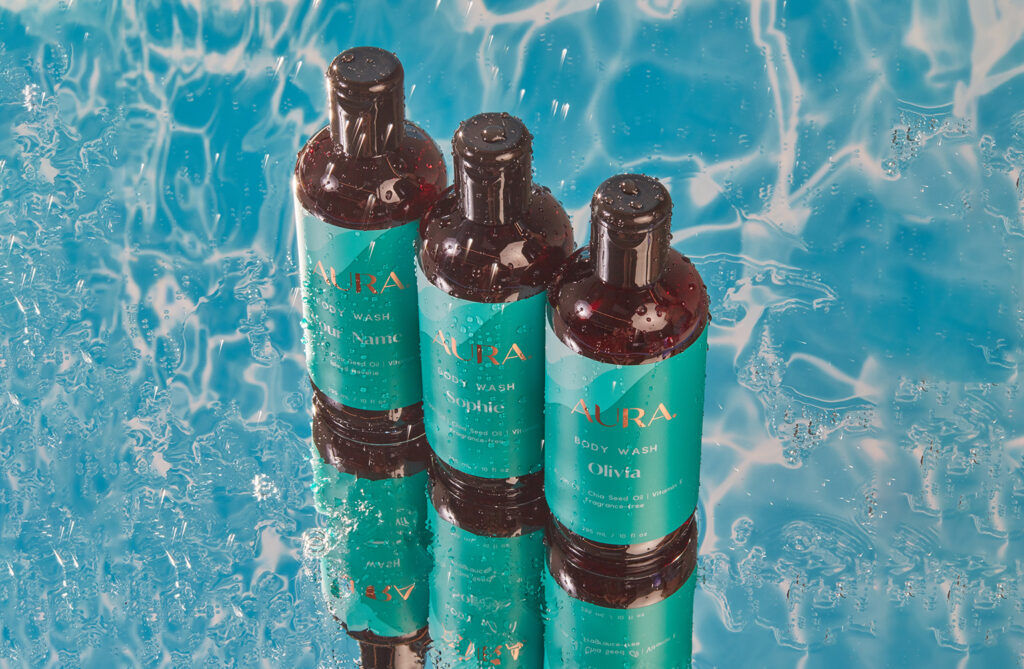 Three bottles of our skin-nourishing body wash against a water-drenched background. 