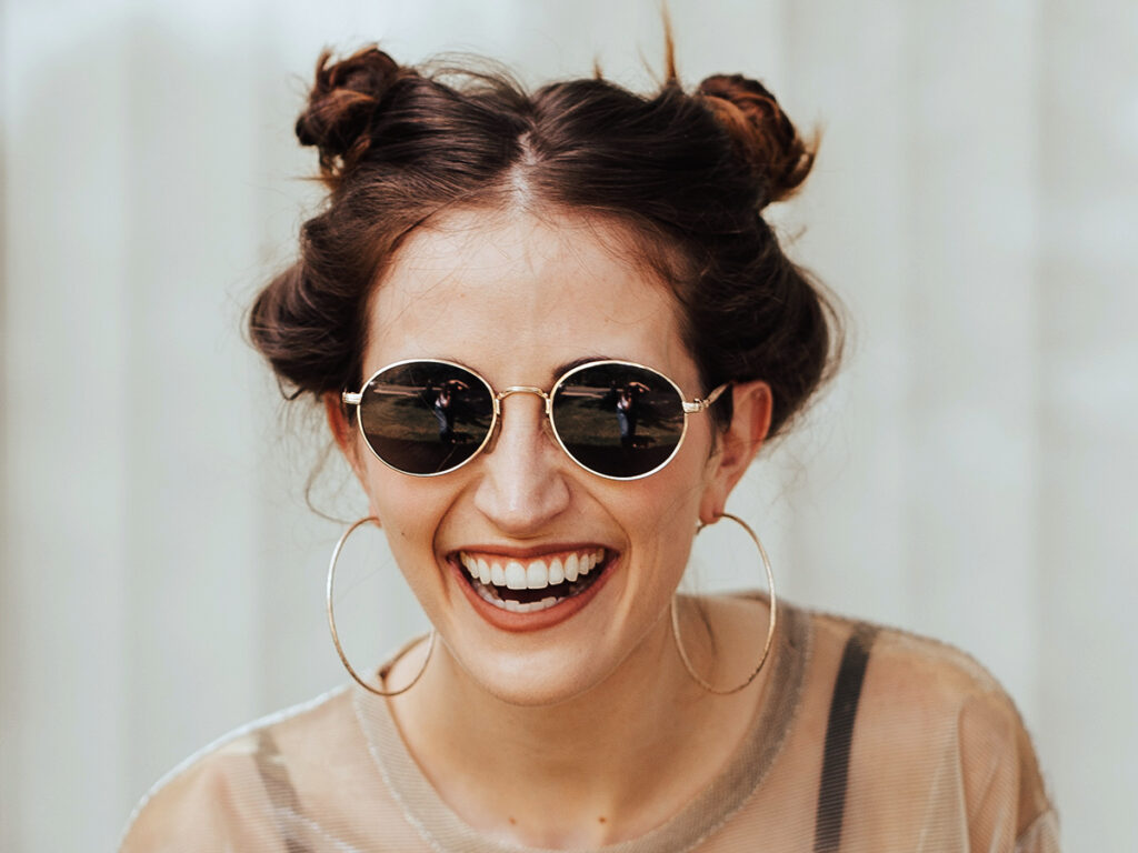 Woman laughing with a space buns hairstyle.